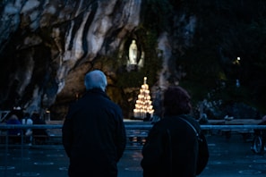A quiet moment of prayer shared between two members in a peaceful garden setting.