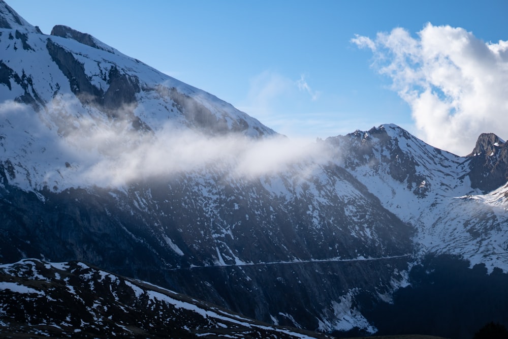 Una montagna coperta di neve e nuvole sotto un cielo blu