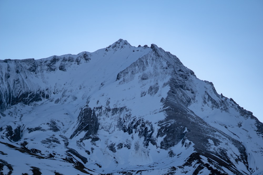 a large mountain covered in snow under a blue sky