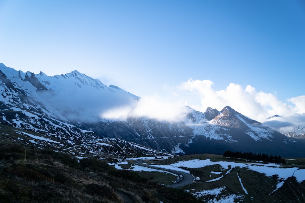 a snow covered mountain range with a winding road in the foreground