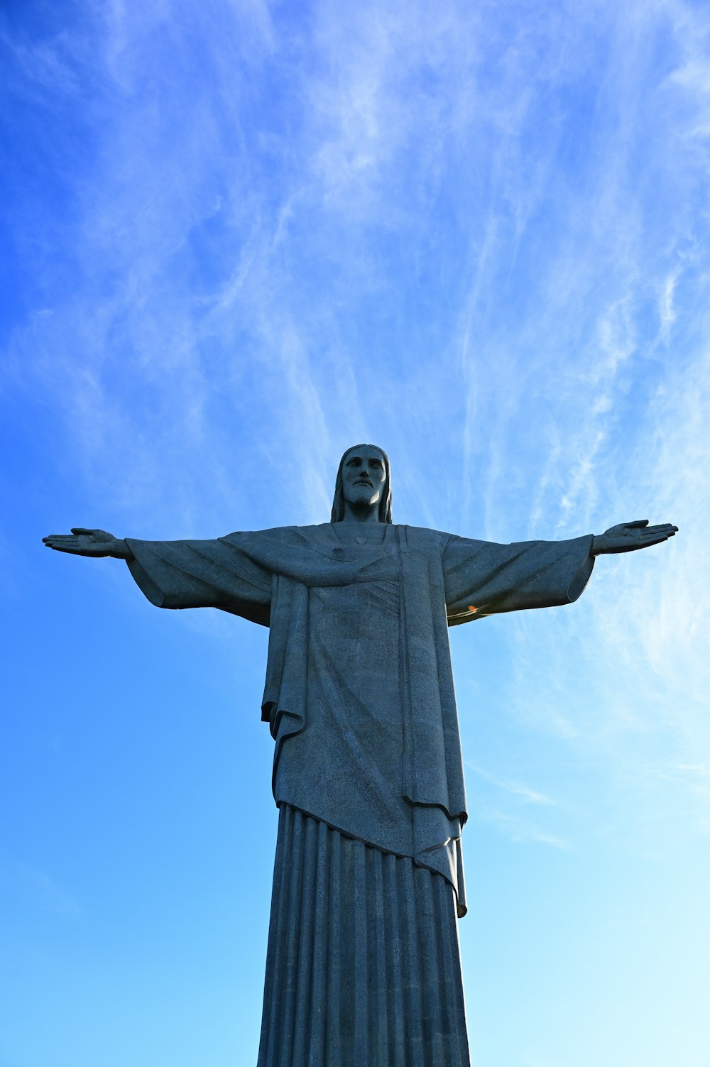 La statua di Cristo si erge di fronte a un cielo blu