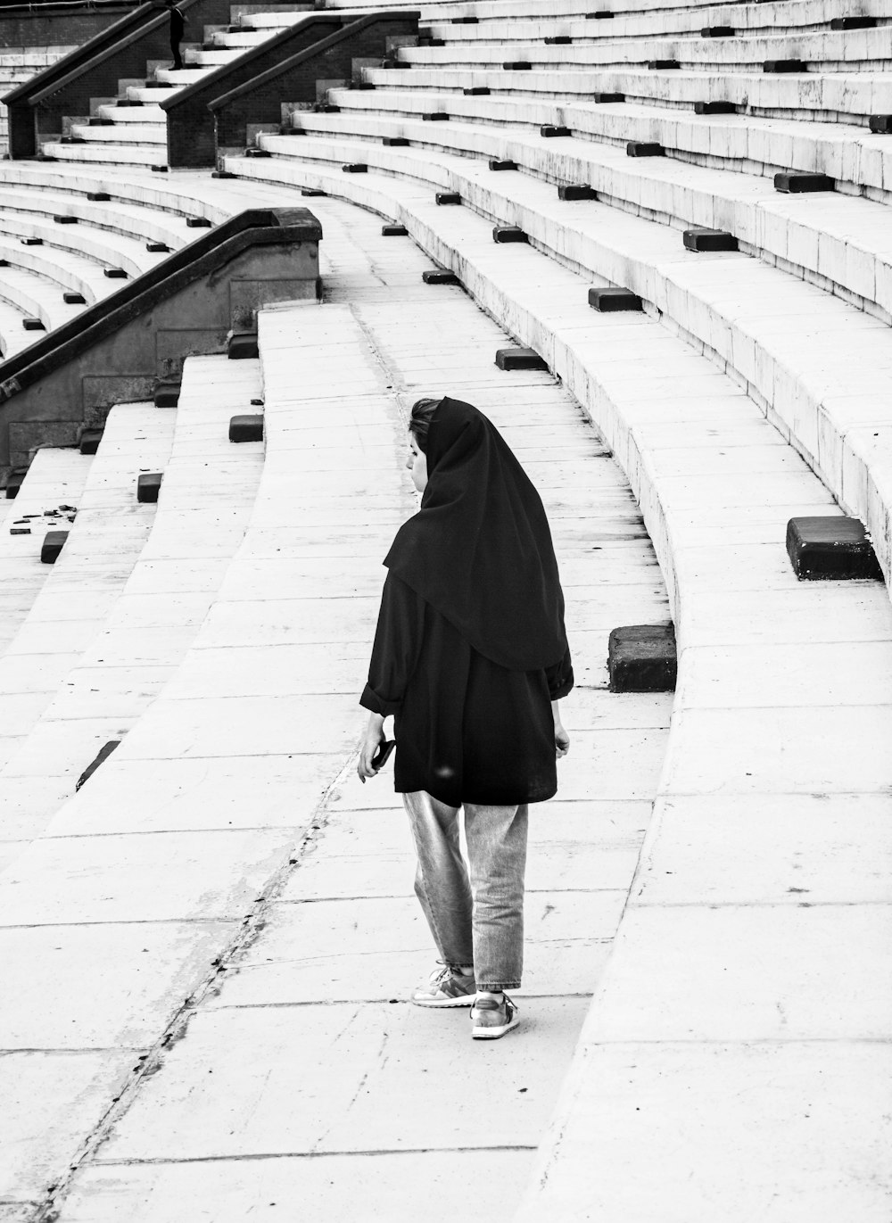 a woman in a black shawl walking in a stadium
