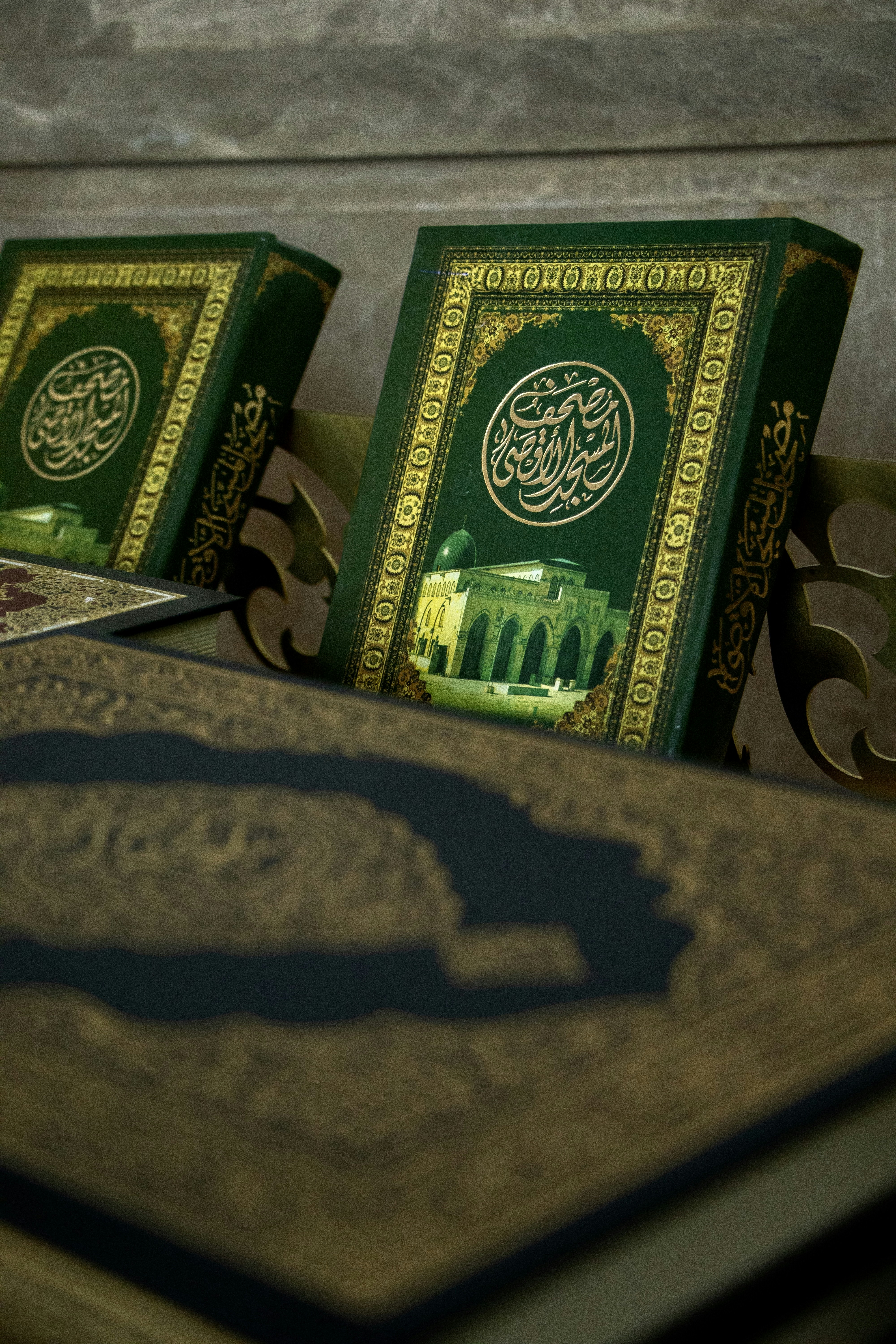 A display of several Quran editions showcasing unique cover designs in green, orange, and blue tones.