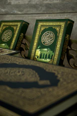Close-up of Quran and Arabic textbooks on a wooden desk with mosque motifs.
