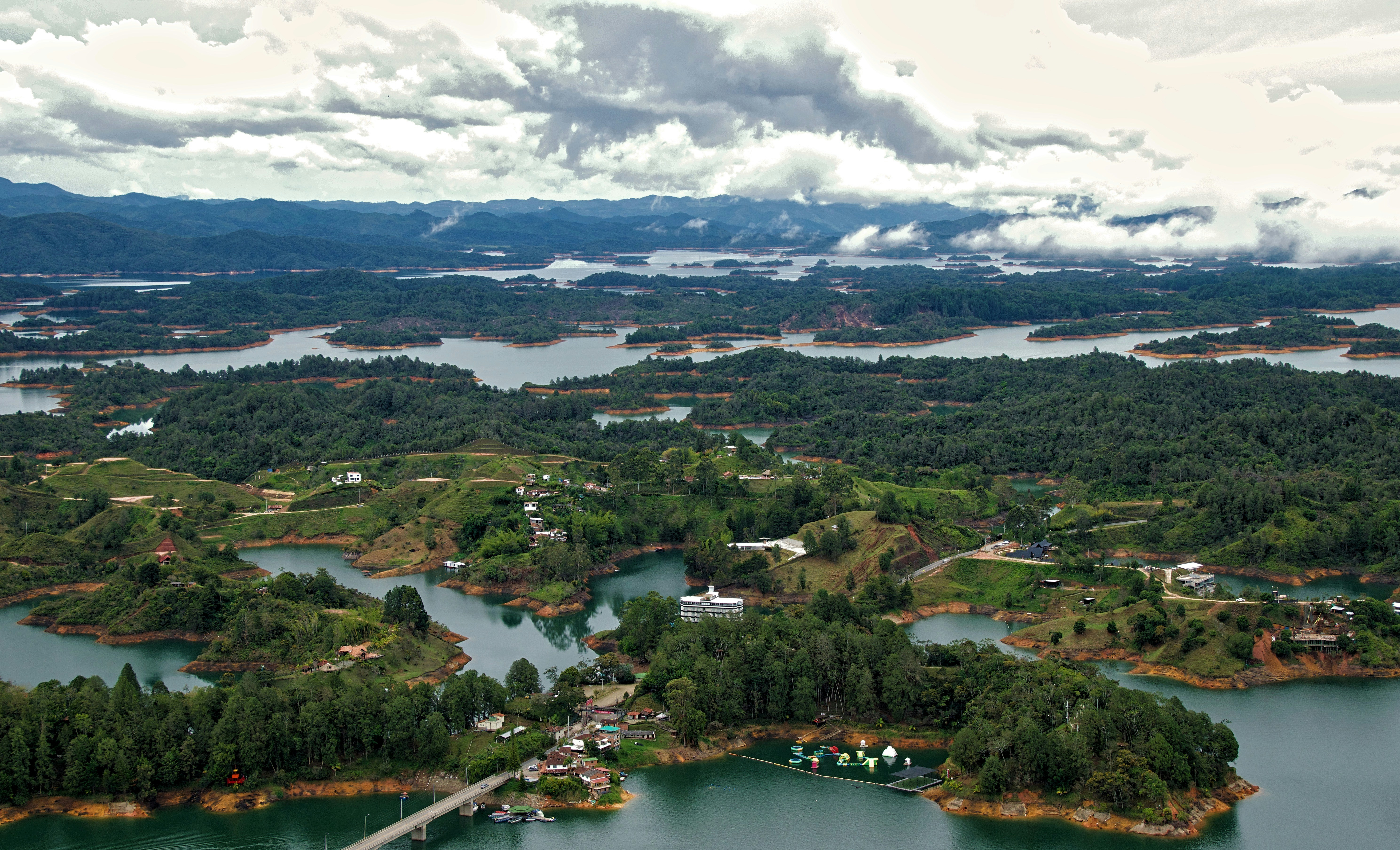 a large body of water surrounded by forest, This photo was taken on El Peñón de Guatapé, Colombia.