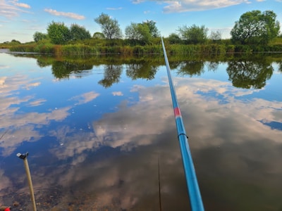 Angler casting a line into a serene pond surrounded by tropical greenery.