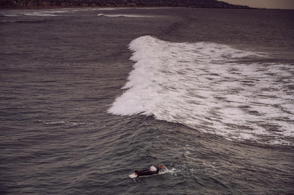 a person swimming in the ocean with a surfboard
