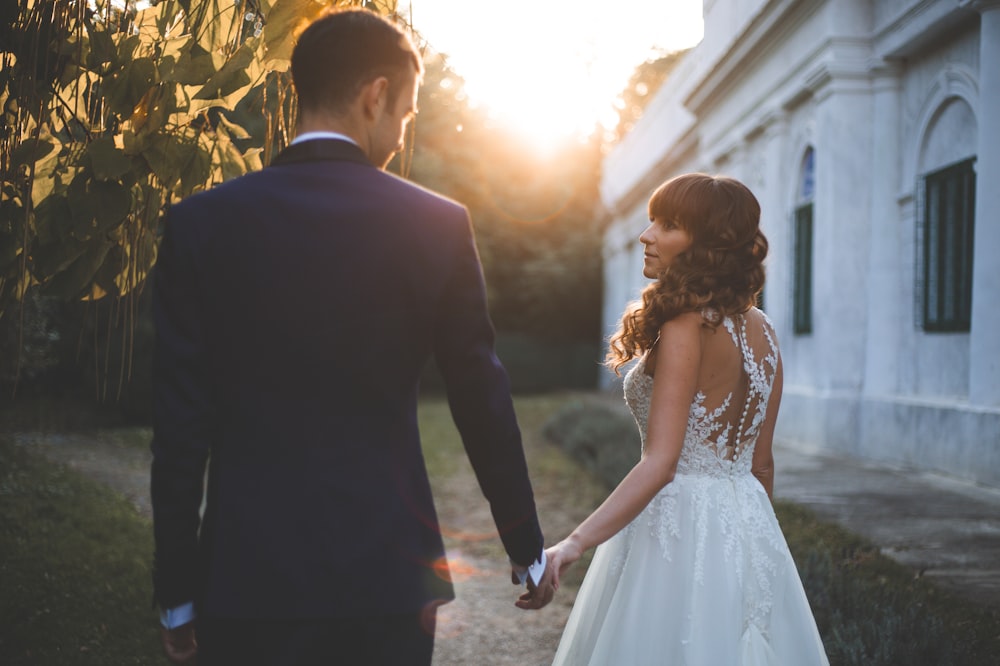 a bride and groom hold hands as the sun sets