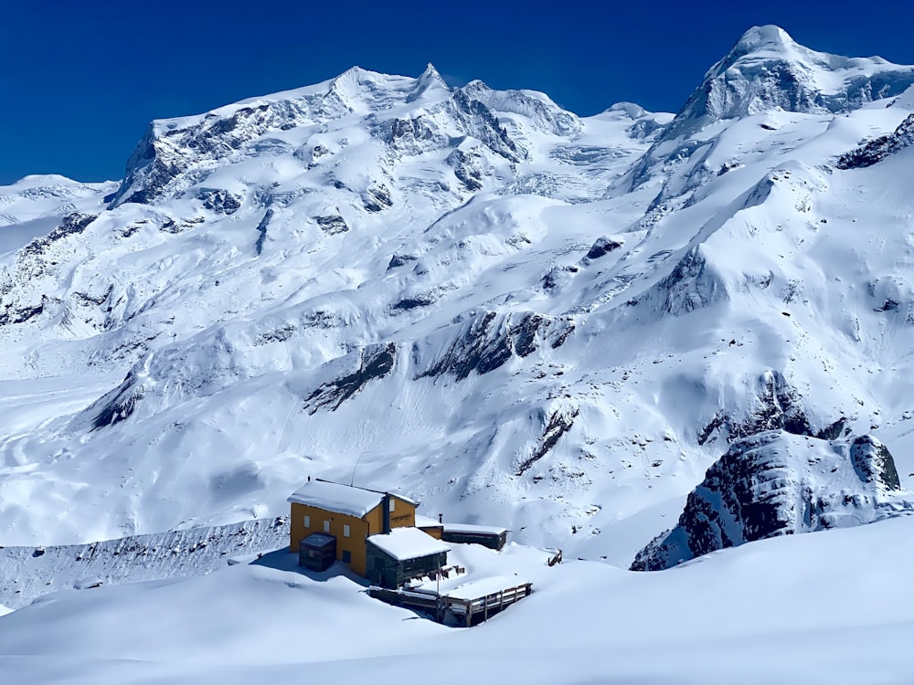 a snow covered mountain with a house in the foreground