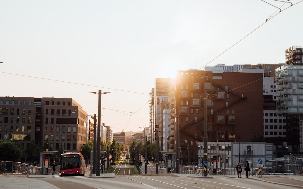 a red bus driving down a street next to tall buildings