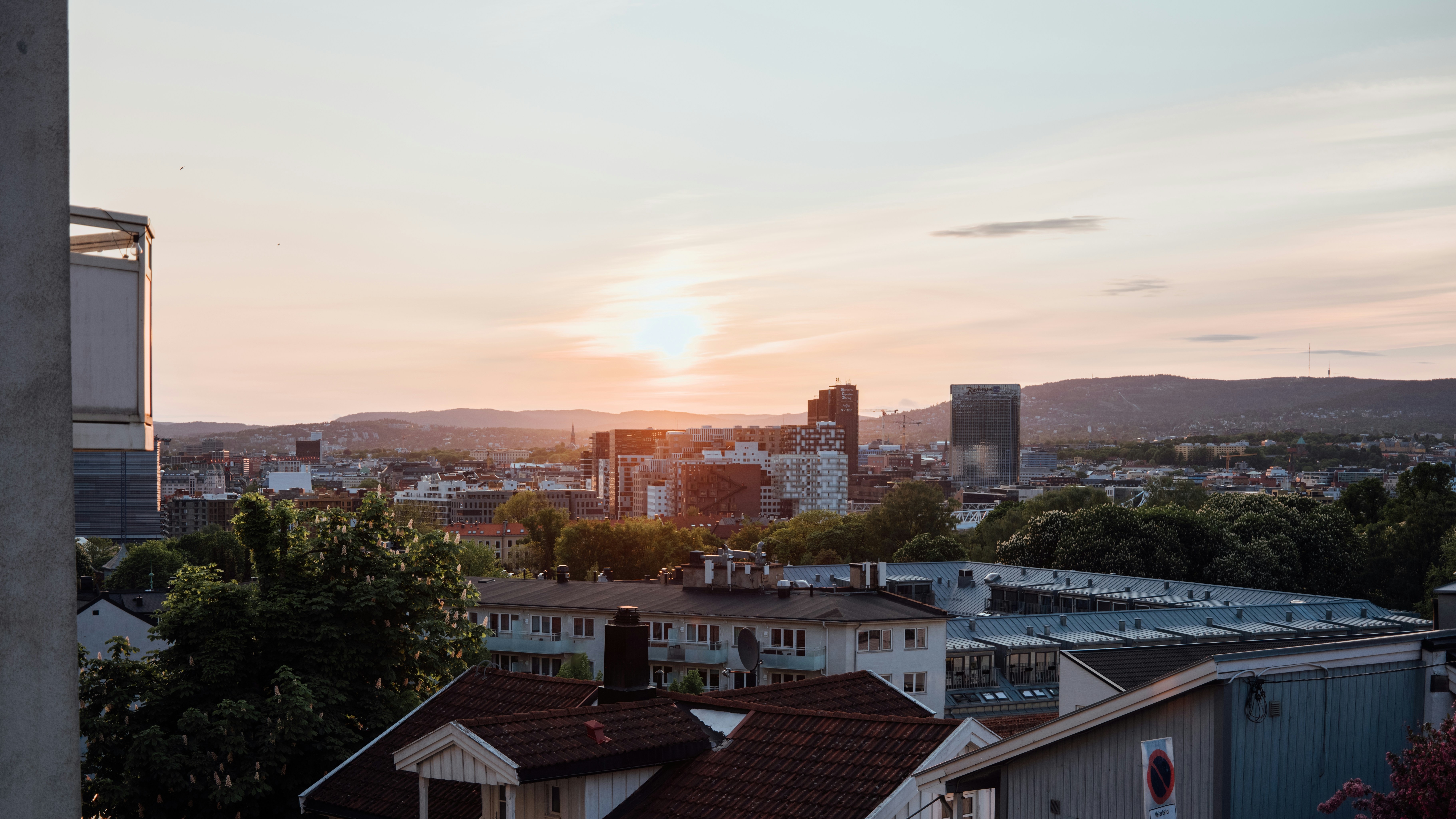 the sun is setting over a city with tall buildings