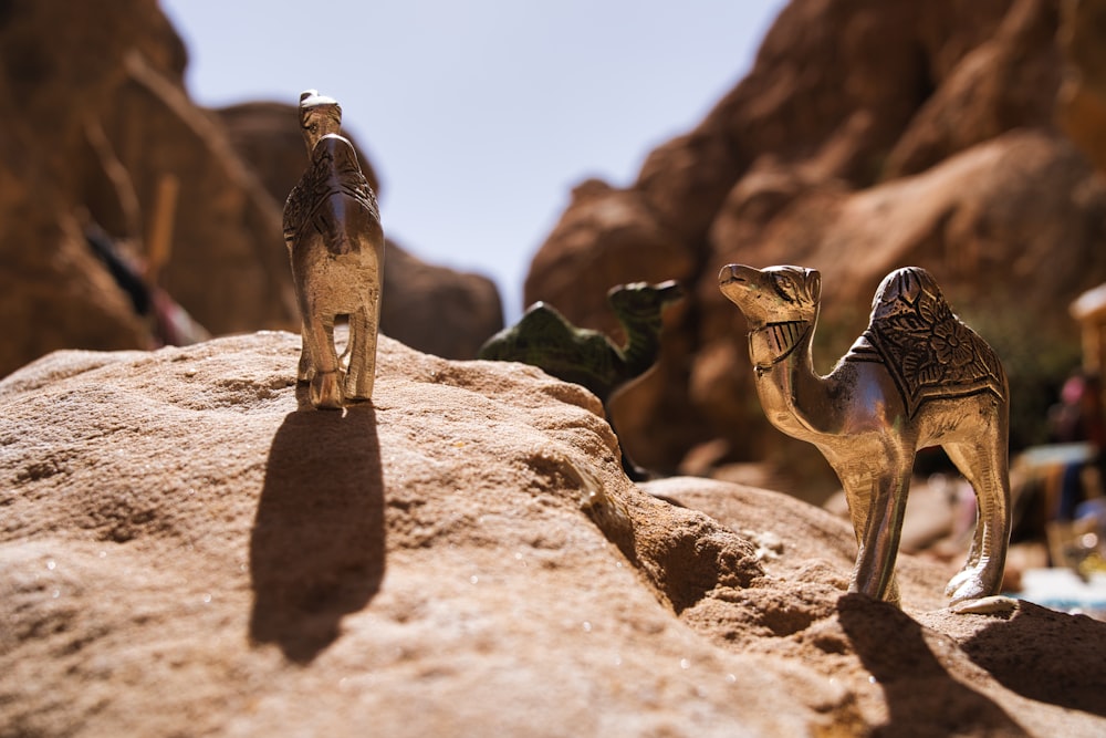 a couple of small toy camels sitting on top of a rock