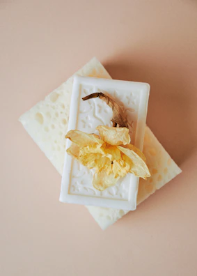 A single pearl essence soap bar resting beside a glass bowl filled with pearls.