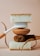 A balanced arrangement of cleaning tools including a white-handled brush, natural fibers, and two thick sponges with contrasting textures.