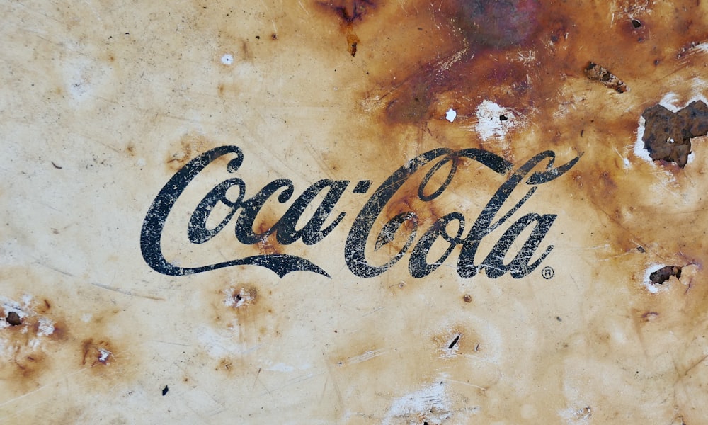 a close up of a coca cola sign on a wall