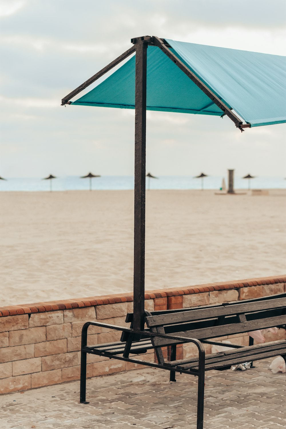 a bench under a blue umbrella on a beach