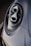 A close-up of a sleek car headlight with a modern and aerodynamic design, featuring intricate details and reflective surfaces. The lighting highlights the smooth contours and craftsmanship.