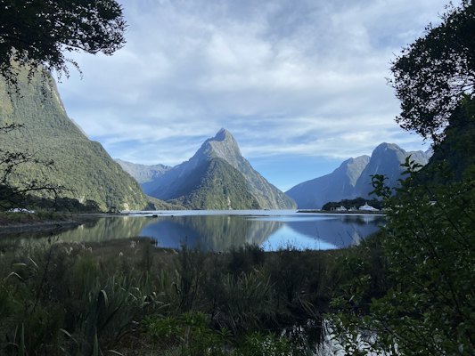 A lake surrounded by mountains under a cloudy sky — Fiordland & Milford Sound, New Zealand