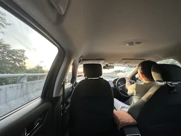 Wide shot of a learner confidently handling a car on an open road during sunset.