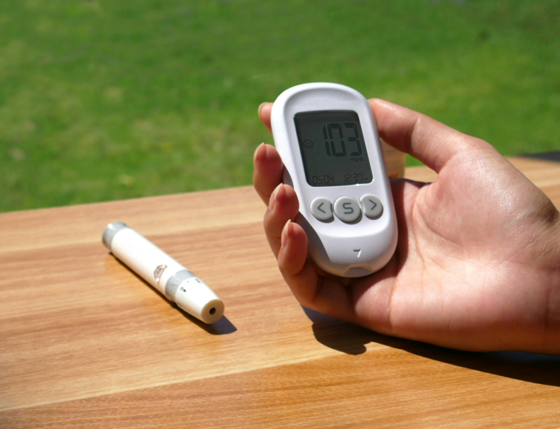 a person holding a digital thermometer next to a pen