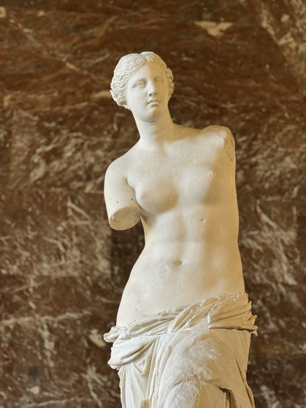 a marble statue of a woman in front of a marble wall