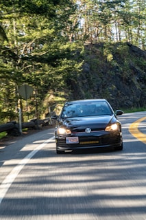 A sleek Volkswagen Golf cruising along a coastal highway with waves crashing nearby.
