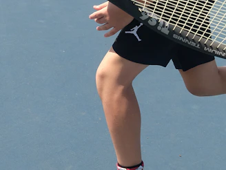 Close-up of a vibrant women's tennis dress in motion on a sunny court.