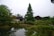 A serene view of a traditional Japanese garden, showcasing lush greenery and a tranquil pond.