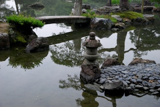 a pond with rocks and a stone lantern in it