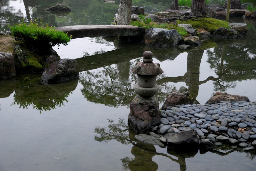 a pond with rocks and a stone lantern in it