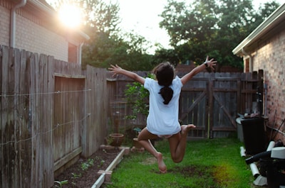 A joyful young girl jumping into a sparkling backyard pool on a sunny day