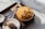 A delicious-looking dessert featuring a bowl of mango shaved ice topped with chunks of cheesecake sits on a dark serving tray. Next to it, a small plate holds an almond croissant. Several silver spoons rest on a beige napkin beside the bowl, all placed on a marble surface.