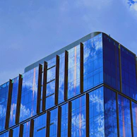 A completed commercial building with sleek glass facades reflecting the sky.