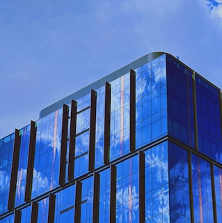 A clean glass facade of a modern building reflecting the sky.