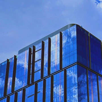 A modern commercial building with sleek glass windows reflecting the sky.