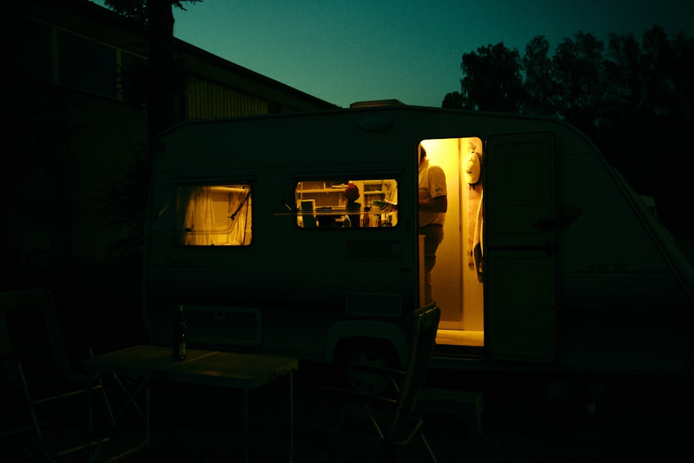 a camper is lit up at night with the door open
