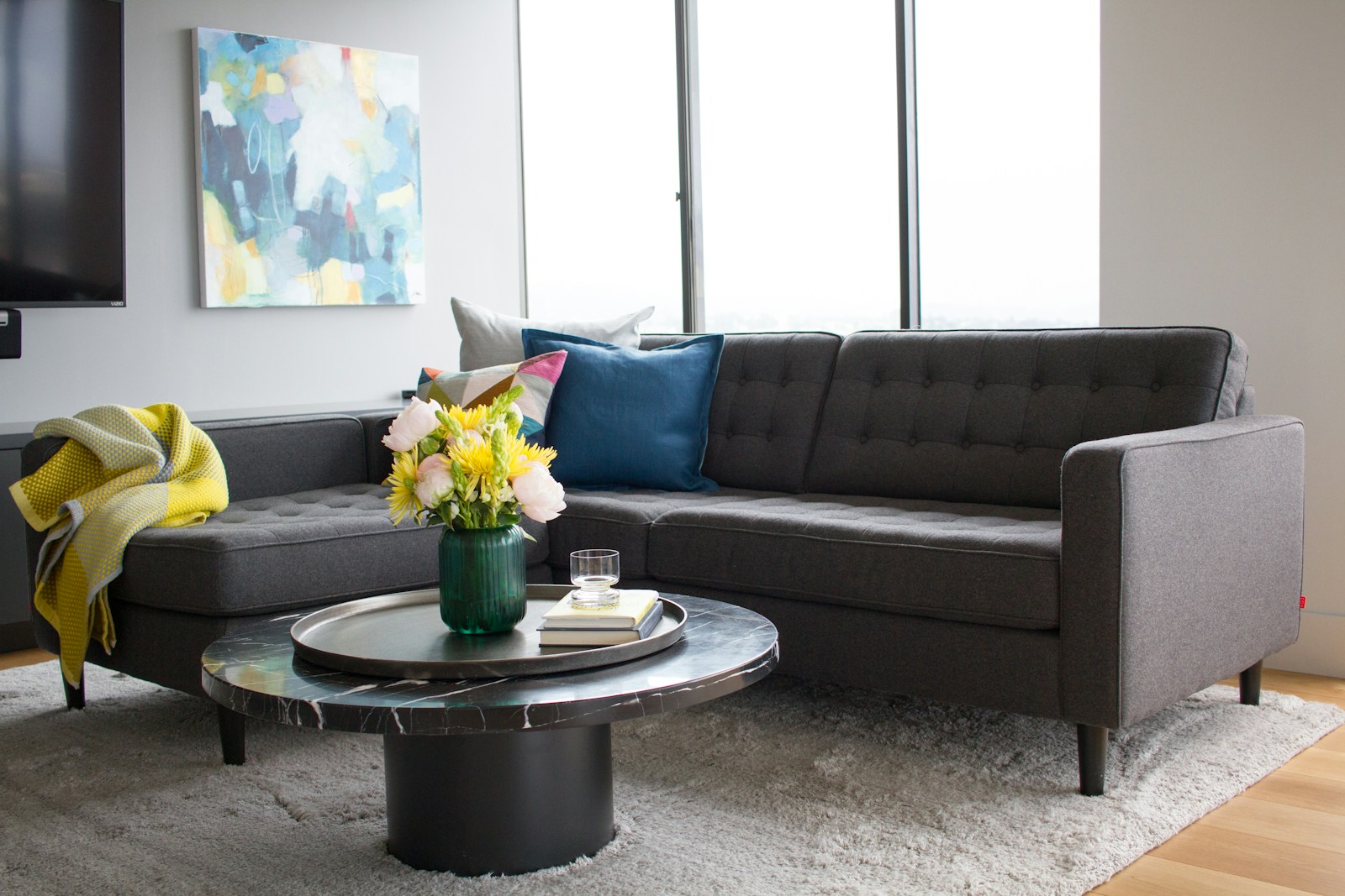 bright apartment with large window dark gray sectional and round coffee table