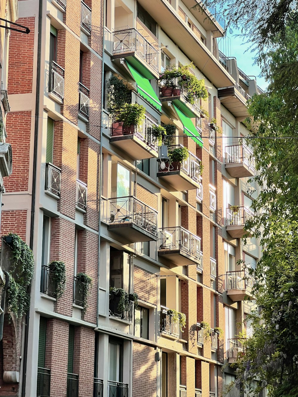 a tall building with balconies and plants on the balconies