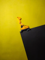 Bright yellow FPV excavator remote control toy with rotating arm in action.