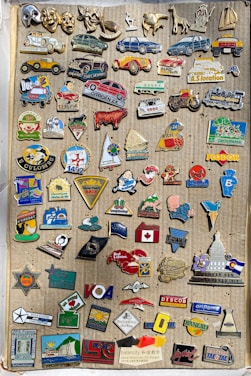 Close-up of colorful custom enamel pins displayed on a rustic wooden board.