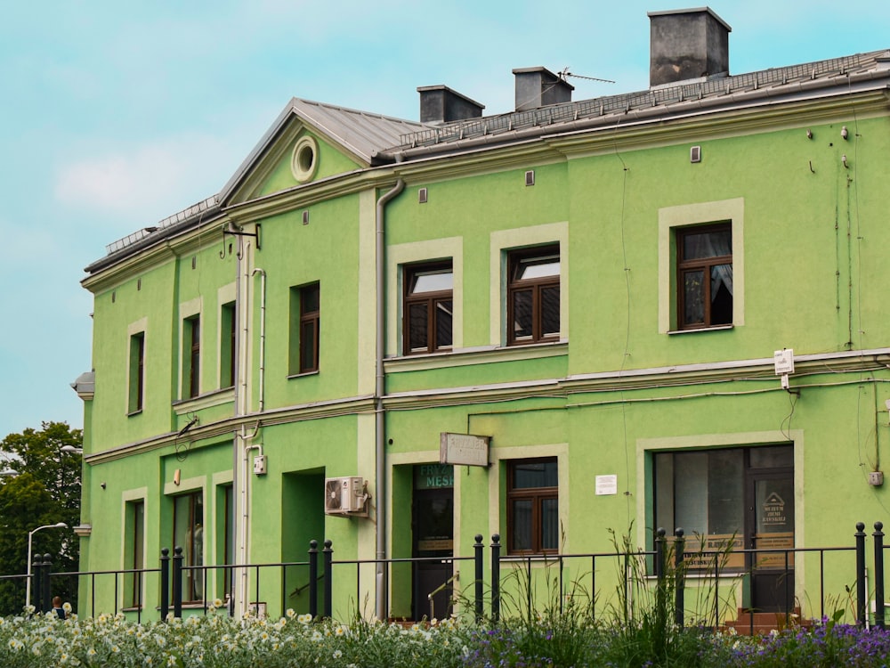 a green building with a clock on the front of it