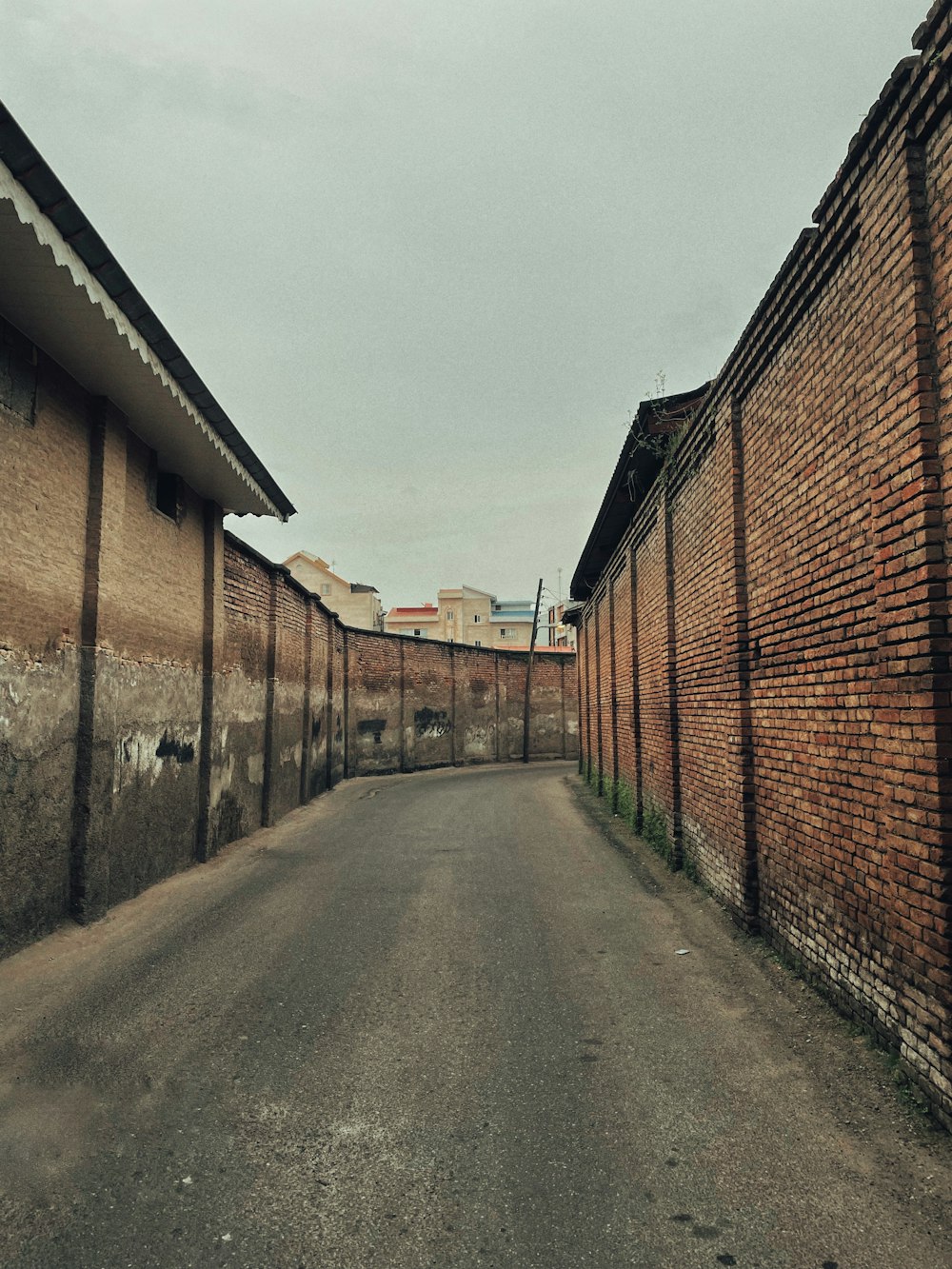 an empty street lined with brick buildings under a cloudy sky