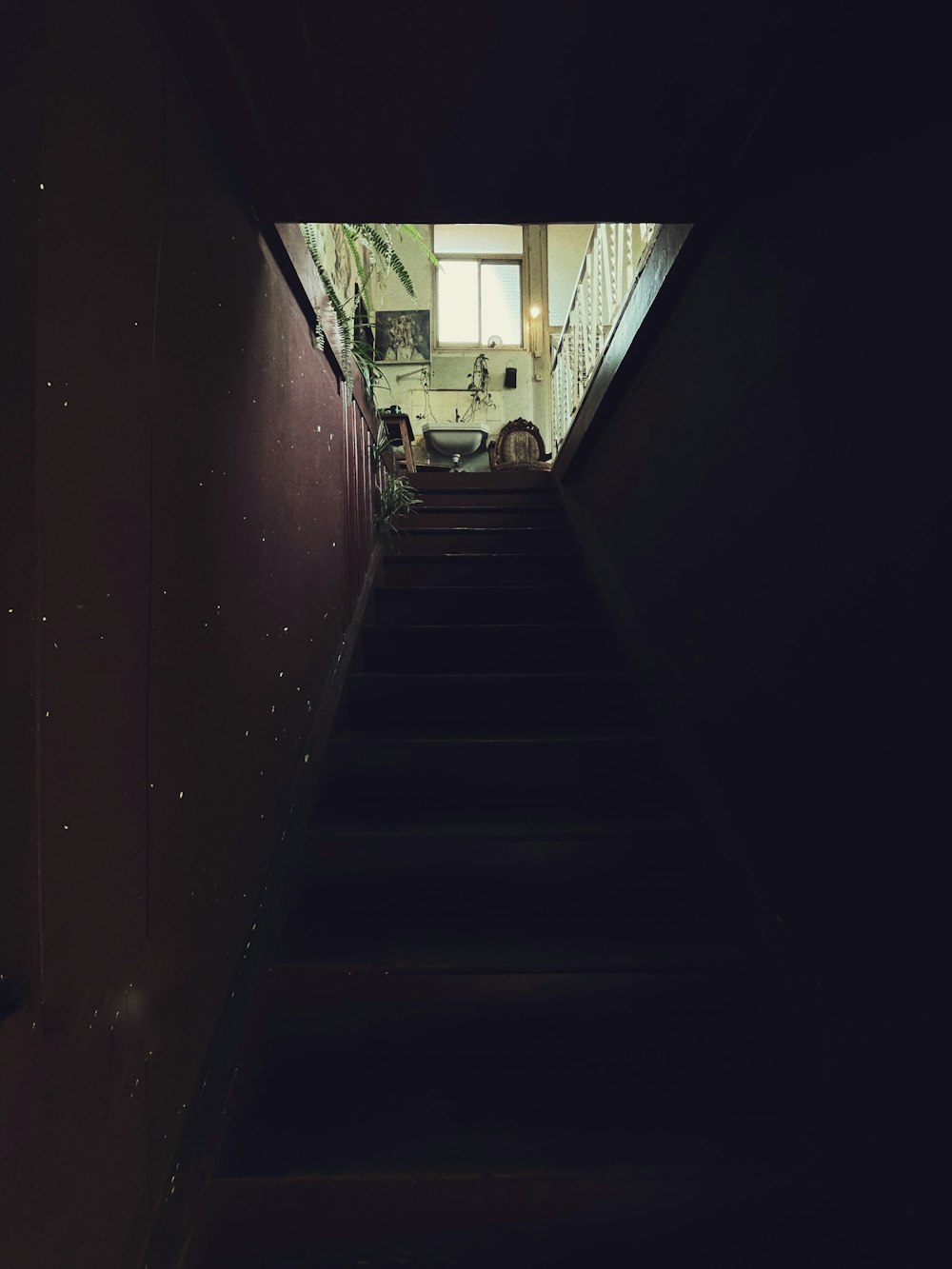 a dark hallway with stairs leading up to a window