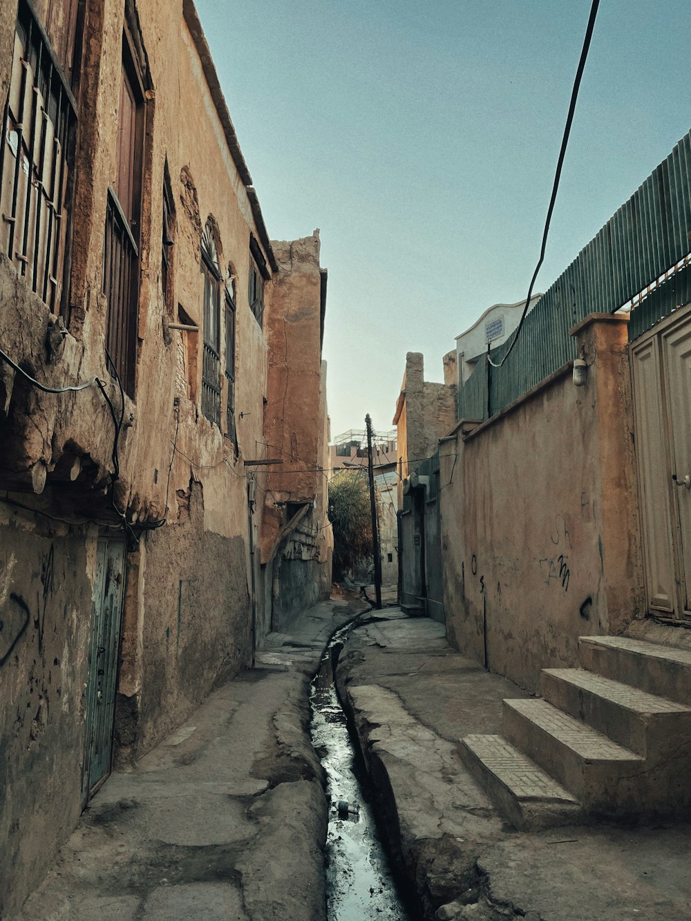 a narrow street with a puddle of water in the middle of it