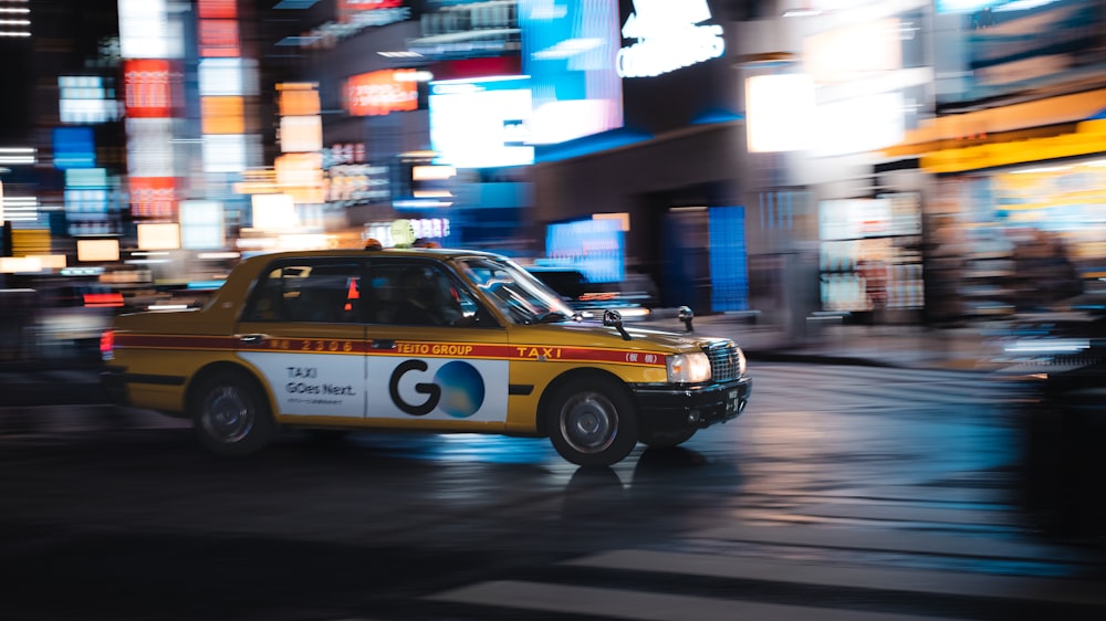 a taxi cab driving down a city street at night