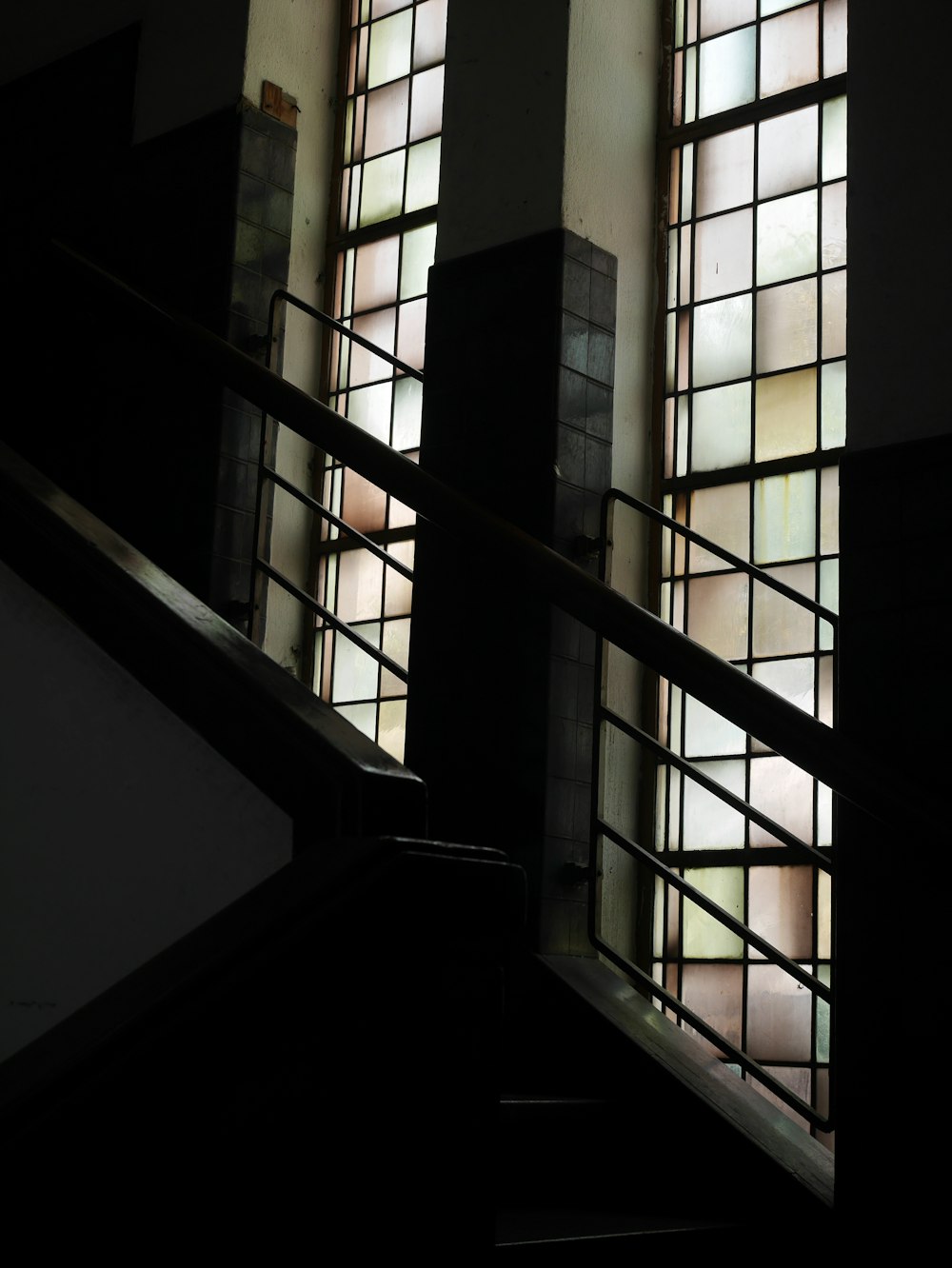 a stair case with three windows and a hand rail