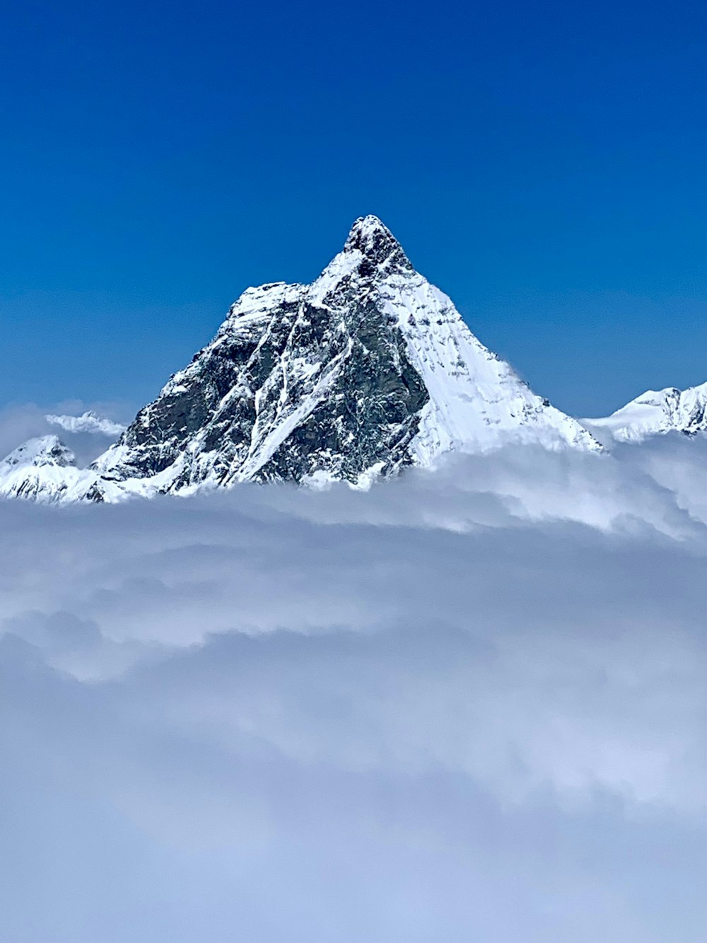 a mountain covered in clouds under a blue sky