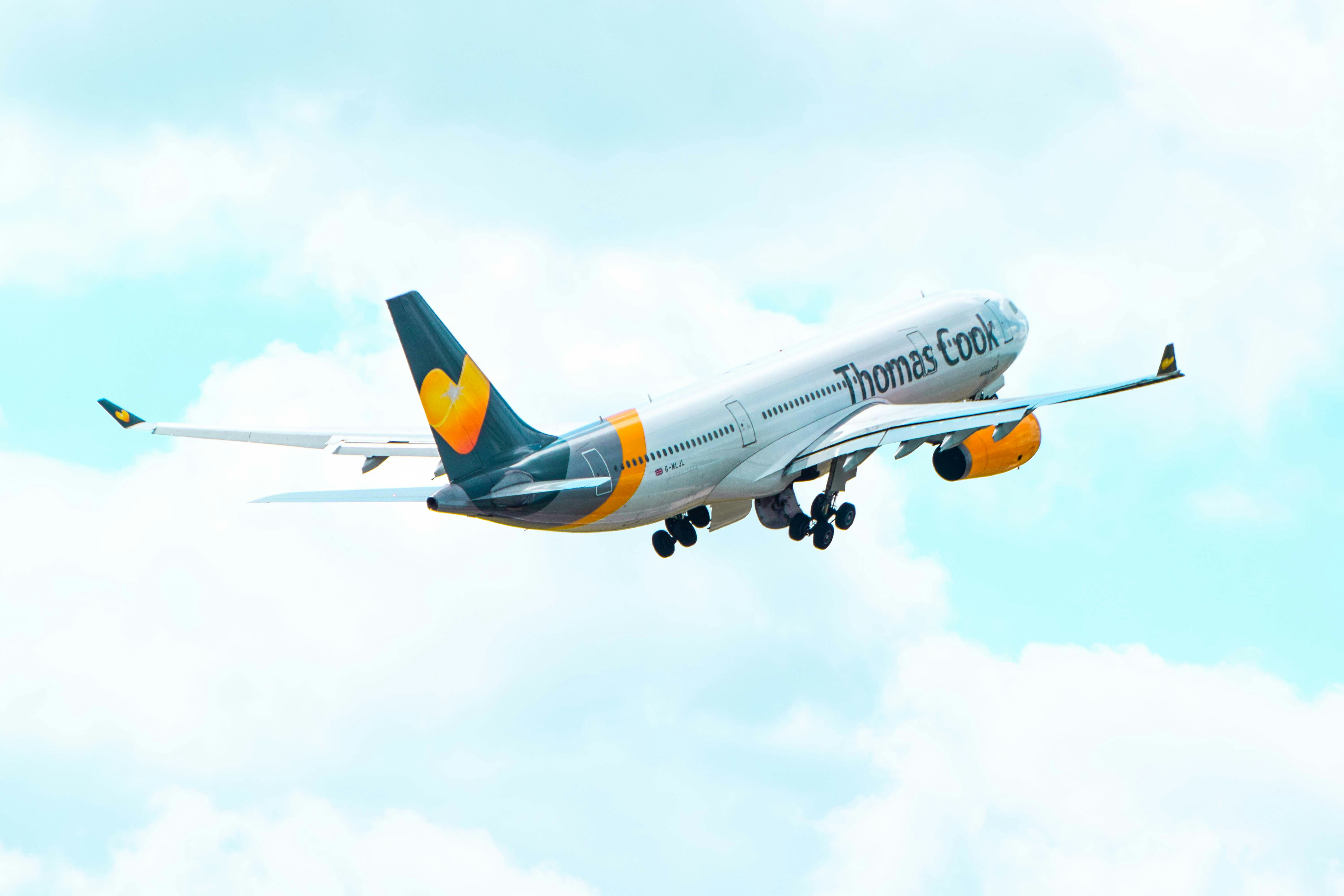 a large jetliner flying through a cloudy blue sky, Thomas Cook airplane taking off