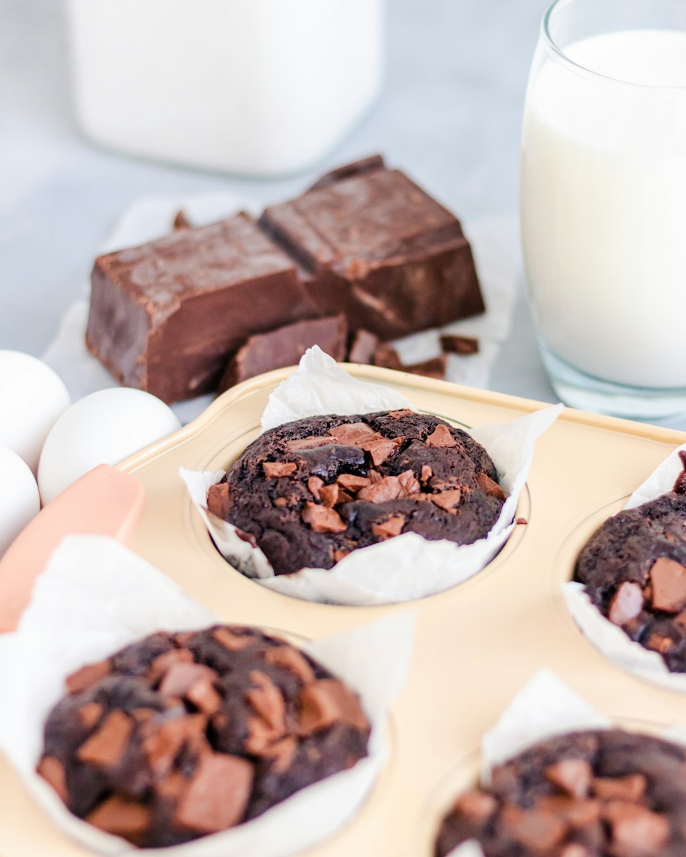 a tray of chocolate cookies next to a glass of milk