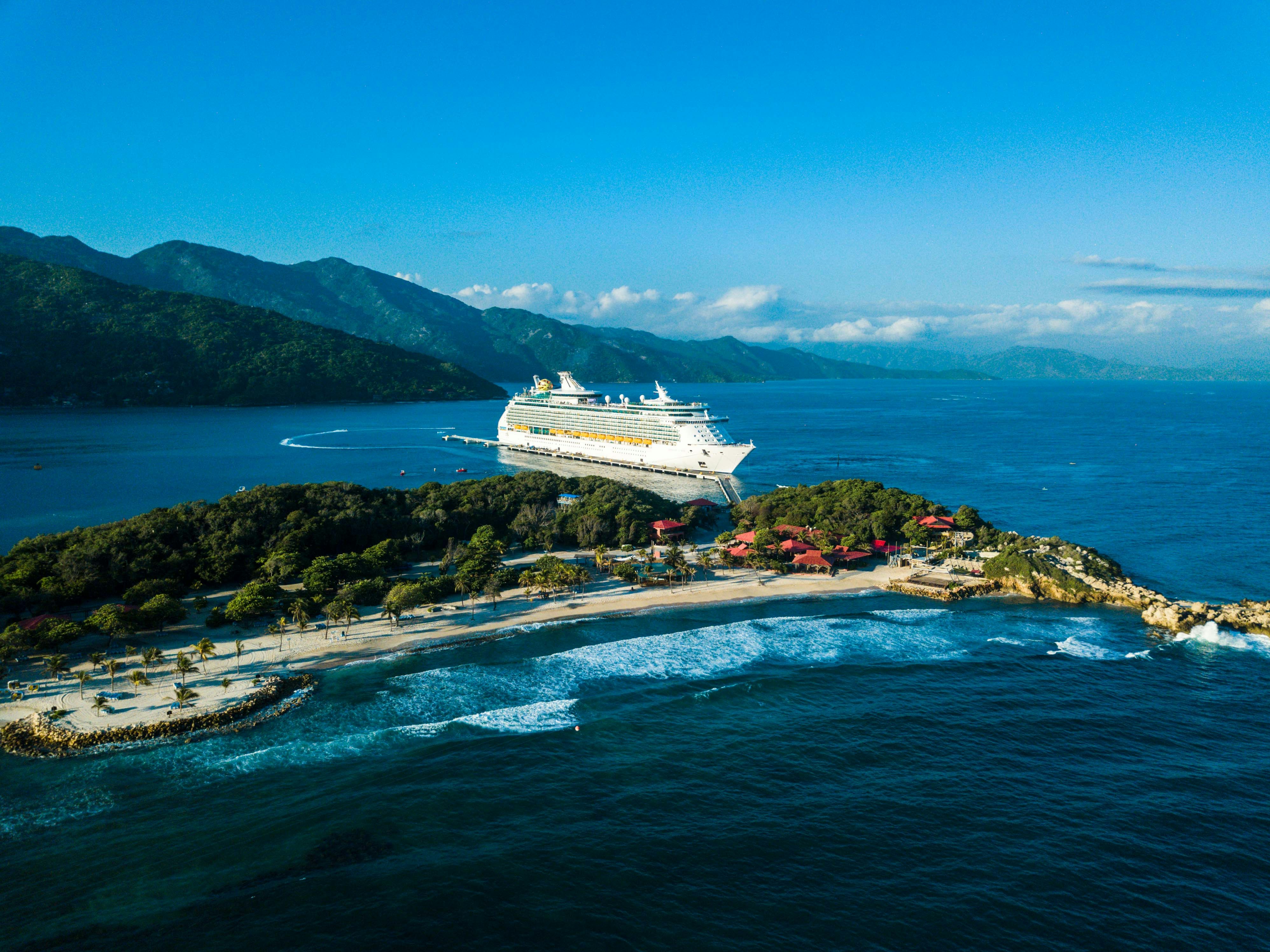 a cruise ship is docked at a small island, Aerial view of a Royal Caribbean cruise ship at port in the Caribbean